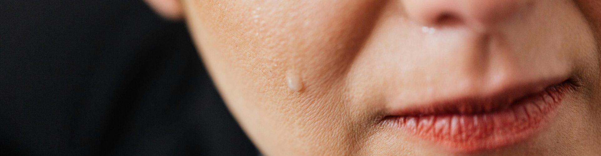 Closeup of crop anonymous sad adult female with makeup crying because of emotional problems